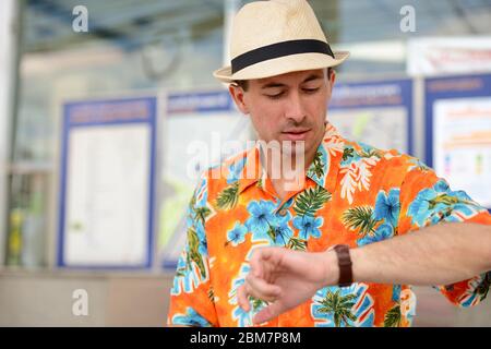 Giovane bel turista che aspetta e controlla l'ora alla stazione della metropolitana Foto Stock