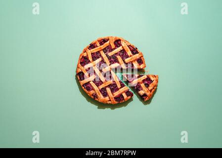 Deliziosa torta ai mirtilli su un tavolo verde sopra la vista. Una fetta di torta. Torta di frutta fatta in casa. Torta di mirtillo su uno sfondo verde piatto Foto Stock