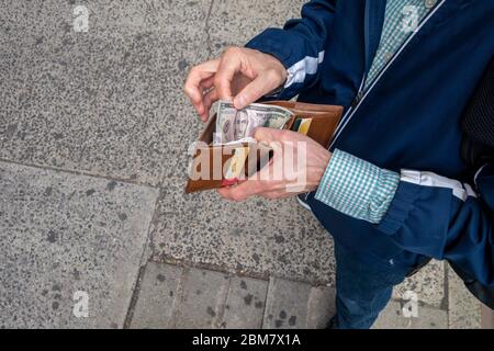 Guardando verso il basso un uomo pronto a fare un pagamento in contanti con denaro in contanti americano fattura di venti dollari Foto Stock