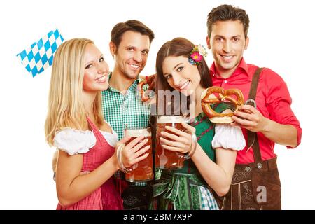 Quattro amici felici all'Oktoberfest festeggiano in dirndls e lederhosen con pretzel e birra Foto Stock