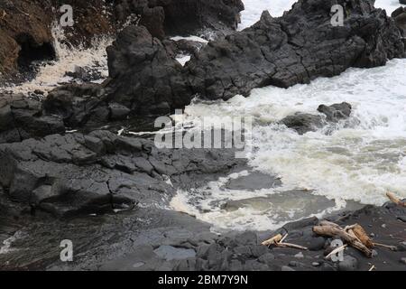Il torrente Palikea attraversa la roccia vulcanica e scorre nell'Oceano Pacifico presso l'Oheo Gulch a Hana, Maui, Hawaii, USA Foto Stock