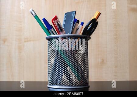 Stativo in metallo con matite, penne, forbici su tavolo in legno Foto Stock