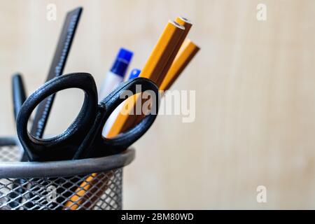 Stativo in metallo con matite, penne, forbici su fondo in legno Foto Stock