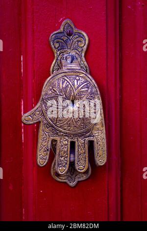 Hand of Fatima, un tipico design marocchino, come un bussare su una porta di legno rosso Foto Stock