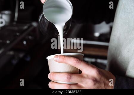 Il barista versa il latte caldo nel caffè. Barista preparante cappuccino, barista preparante la bevanda di caffè. Take away Foto Stock