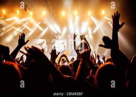 Le silhouette nere della gente di concerto di rock davanti alle luci del palco luminose Foto Stock