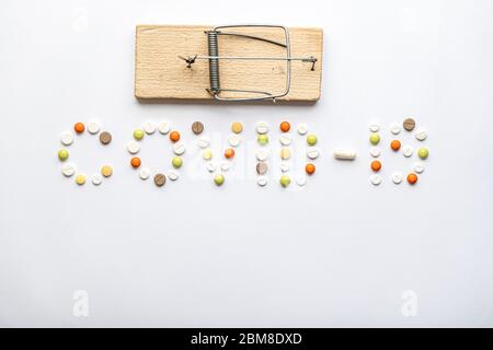 iscrizione covid-19 con pillole e capsule e mousetrap in legno in layout su uno spazio copia sfondo bianco. Coronavirus, medicina e salute, sicurezza Foto Stock