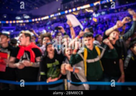 Sfondo sfocato di un evento di eSport - un sacco di fan su una tribuna all'arena del torneo con le mani sollevate. Rallegrarsi per la loro squadra preferita. Foto Stock