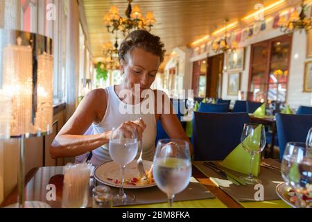 Donna matura bella con capelli corti mangiare al ristorante Foto Stock