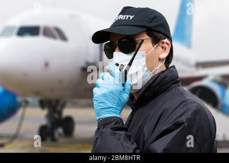 Guardia di sicurezza che parla sul Walkie Talkie vicino all'aereo Foto Stock