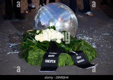 07 maggio 2020, Amburgo: Una corona funeraria si trova accanto a una palla da discoteca scoppiata a una protesta di restauratori di quartiere, club e proprietari di pub su Beatles Platz di fronte al Große Freiheit sulla Reeperbahn. Nel quartiere di culto di Amburgo, St. Pauli, i proprietari di bar e pub hanno attirato l'attenzione sulle loro esigenze esistenziali il giovedì sera a causa della crisi Corona e hanno chiesto più aiuti finanziari. L'iniziatore dell'azione di protesta sulla Reeperbahn era Dragqueen O. Jones, che gestisce diversi bar nel quartiere stesso. (Al dpa "barre di rieperbahn in difficoltà - "assenza di luce alla fine del tunnel") Foto Stock