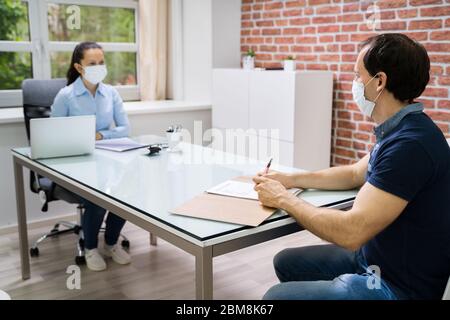 Incontro d'affari di intervista di lavoro all'ufficio di legge che indossa la maschera facciale Foto Stock