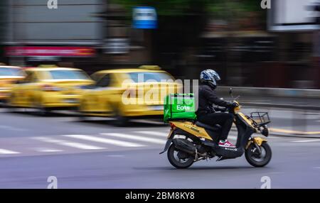 Bucarest, Romania - 07 maggio 2020: Un Uber mangia il corriere di consegna del cibo su uno scooter in alta velocità. I ristoranti sono chiusi e sono consentite solo le consegne Foto Stock