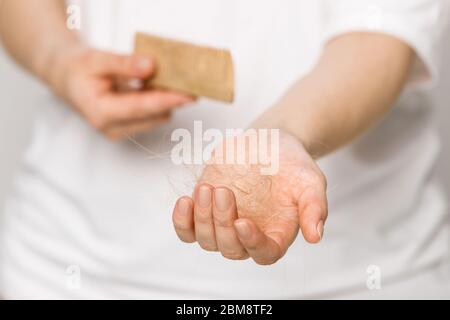 Donna che perde i capelli dopo aver pettinato in mano la spazzola, fuoco selettivo. Perdita di capelli problema, periodo postpartum, disturbi mestruali o endocrini, stress, Foto Stock