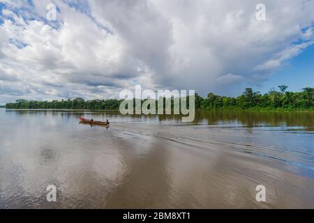 Brokopondo, Suriname - Agosto 2019: Cielo drammatico con barca a vela lungo le acque marroni del fiume Suriname. Foto Stock