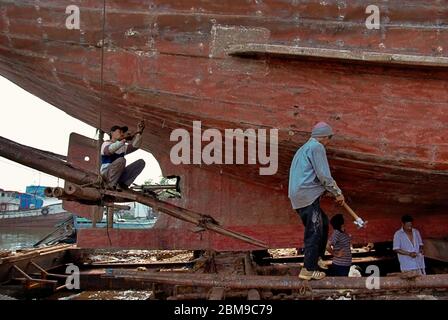 Lavoratori che riparano una nave phinisi in un molo nella zona portuale di Sunda Kelapa, Penjaringan, Giacarta, Indonesia. Foto Stock