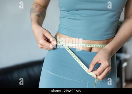 Una giovane donna asiatica misura la vita con un righello Foto Stock