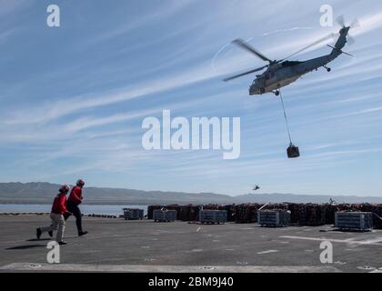 200506-N-MM155-1415 OCEANO PACIFICO (6 maggio 2020) Capo Aviazione Ordnanceman Liezl Fisco, sinistra, E il Mate di Gunner, terza classe Peter Fellman, assegnato alla nave d'assalto anfibia USS Boxer (LHD 4), corre attraverso il ponte di volo come un MH-60S Seahawk attaccato all'elicottero Sea Combat Squadron (HSC) 21 solleva la lancia dal ponte di volo durante un trasferimento di munizioni. Boxer sta conducendo operazioni di routine nel Pacifico orientale. (STATI UNITI Foto Navy di Mass Communication Specialist Seaman apprendista Logan A. Southerland) Foto Stock