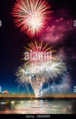 Colorato Capodanno Fireworks Display illuminare il cielo e l'acqua al largo di Brighton Jetty, Adelaide, Australia del Sud Foto Stock