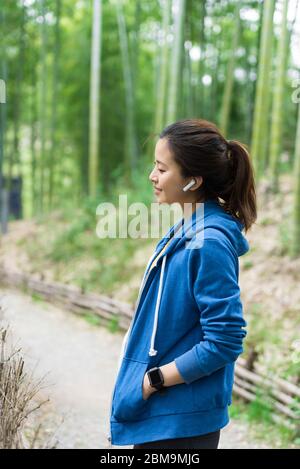 Una giovane donna asiatica cammina e riposa in una foresta di bambù Foto Stock