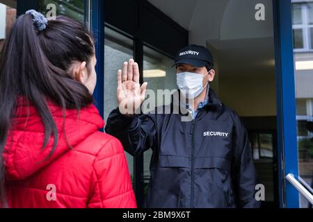 Protezione in uniforme e maschera facciale che fa il gesto di stop mano Foto Stock