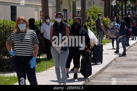 Orlando, Stati Uniti. 7 maggio 2020. Le persone che indossano maschere protettive attendono in fila per ricevere assistenza alimentare fornita dalla seconda Harvest Food Bank della Florida centrale in occasione di un evento di distribuzione alimentare organizzato da volontari presso la Chiesa di Calvario. Le banche alimentari di tutti gli Stati Uniti sono sopraffatte a causa delle migliaia di persone che hanno perso il lavoro a causa della pandemia del coronavirus (COVID-19). Credit: SOPA Images Limited/Alamy Live News Foto Stock