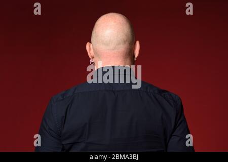 ritratto di un uomo calvo,vista posteriore,su sfondo rosso Foto Stock