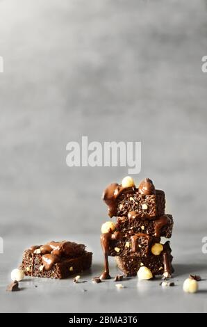 Pila di pezzi di brownie con nocciola su un tavolo grigio con sfondo grigio. Foto Stock