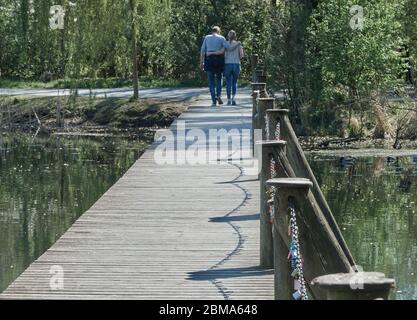 Braunschweig, Germania, 18 aprile 2020: Giovani coppie di passeggini abbracciati sopra il ponte pedonale in legno sul lago Foto Stock