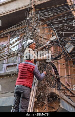 Kathmandu, Nepal - 7 gennaio 2020: I lavoratori riparano una moltitudine di cavi elettrici intrecchiati a Kathmandu, in Nepal Foto Stock