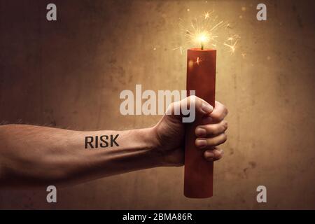 Concetto di rischio - mano che tiene un bastone di dinamite bruciante Foto Stock