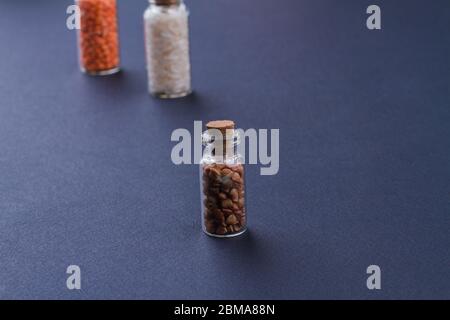 Tre mini bottiglie riempite con chicchi crudi. Foto Stock