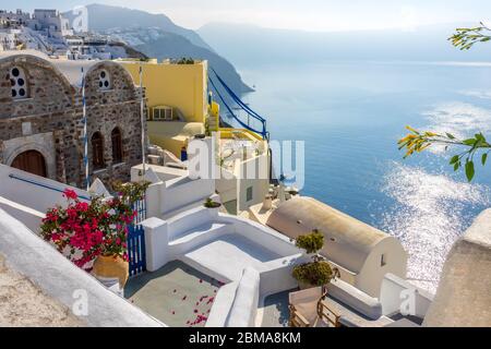 Grecia. Giornata estiva di sole a Santorini. Edifici e terrazze con fiori sulla caldera che si affaccia sul mare Foto Stock
