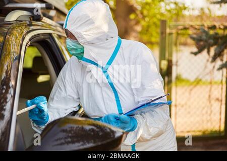 Test del coronavirus con tampone alla gola nella stazione di test drive-in mediante scout di contenimento del reparto sanitario Foto Stock