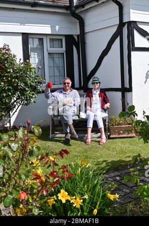 Littlehampton UK 8 maggio 2020 - una coppia fare un brindisi per commemorare l'anniversario della VE Day nel villaggio di Ferring vicino Worthing durante le restrizioni di blocco del coronavirus COVID-19 pandemic. E '75 anni da quando la vittoria in Europa sui tedeschi è stata annunciata durante la seconda guerra mondiale: Credit Simon Dack / Alamy Live News Foto Stock