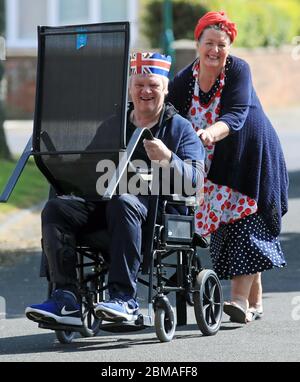 Un uomo e una donna spostano una sedia davanti alle celebrazioni della loro strada in Duncan Avenue, Redcar, per celebrare il 75 ° anniversario di VE Day. Foto Stock