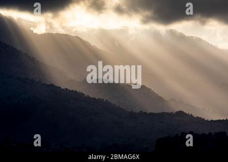 Raggi di sole che piercing nuvole oscure sopra le montagne a Creta, Grecia Foto Stock