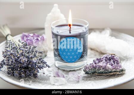 Candela di vetro bruciante con segno fatto in casa che mostra simbolo di Fiore della vita in casa interni con semi-preziose pietre geodes. Simboli spirituali in casa. Foto Stock