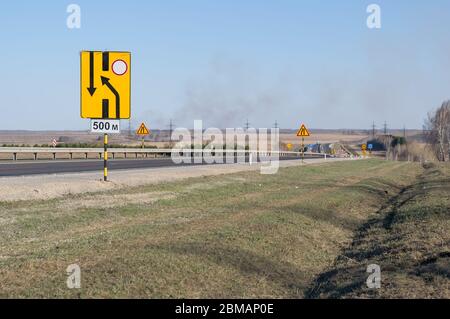 vista di un gran numero di segnali di avvertenza per la riparazione stradale su una strada statale su una nuova superficie asfaltata in una zona collinare Foto Stock