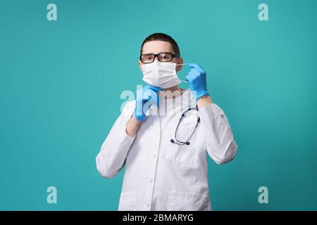 Medico con stetoscopio mette sulla sua faccia una maschera medica protettiva. Foto Stock