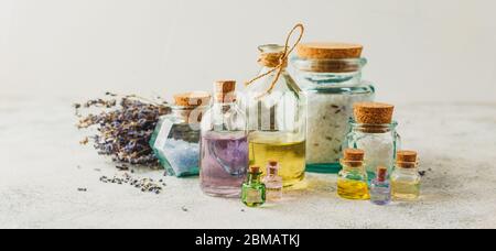 Oli aromatici in bottiglie di vetro, sali aromatici e lavanda secca. Concetto naturale ovranico skincare cosmetic. Foto Stock