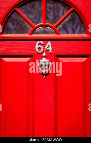 Casa numero 64 su una porta di legno rosso Foto Stock