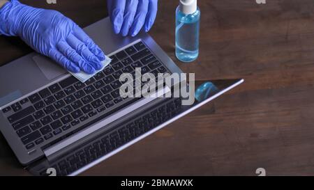 Disinfezione della tastiera di un computer. Le mani nei guanti eseguono la lavorazione antisettica delle superfici di lavoro. Necessaria misura preventiva nella lotta Foto Stock