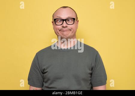 Uomo pazzo in occhiali facendo facce divertenti squinting occhi Foto Stock