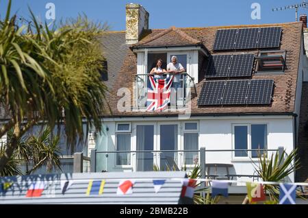 Littlehampton UK 8 maggio 2020 - i residenti sul loro balcone a Ferring vicino Worthing commemorano l'anniversario del VE Day durante le restrizioni di blocco del coronavirus COVID-19 pandemic. E '75 anni da quando la vittoria in Europa sui tedeschi è stata annunciata durante la seconda guerra mondiale: Credit Simon Dack / Alamy Live News Foto Stock