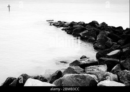 Rocce, il mare e un posto marcatore, Inghilterra Foto Stock