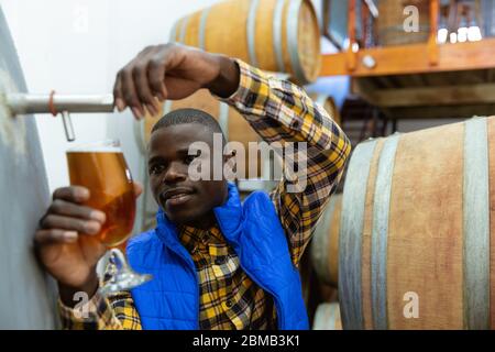 Uomo afro-americano che lavora in una microbirreria Foto Stock