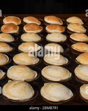 Tipici poffertjes olandesi - piccole frittelle-essendo cotte su una pentola pesante di ferro in preparazione durante il festival di cibo di strada, un evento all'aperto, traditiona Foto Stock