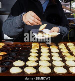 Tipici poffertjes olandesi - piccole frittelle-essendo cotte su una pentola pesante di ferro in preparazione durante il festival di cibo di strada, un evento all'aperto, traditiona Foto Stock