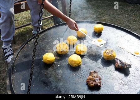 Palle di polenta e formaggio al centro di essa, chiamato bulz, un piatto tradizionale rumeno. Tostatura di polenta e formaggio alla griglia all'esterno, con pecora Foto Stock